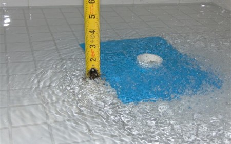 A waterproofed bathroom floor with the drain plugged and standing water for a flood test